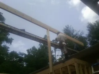 Carpenter setting a ridge beam over a new addition frame — Ice Dam Removal by Roofing Brothers in Jamaica
