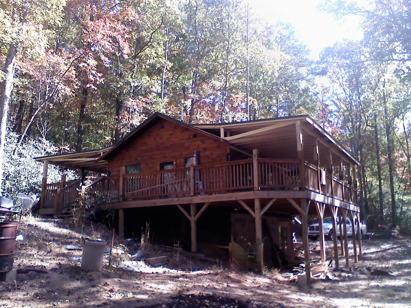Log cabin with a wraparound porch and metal roof in the fall in Jamaica