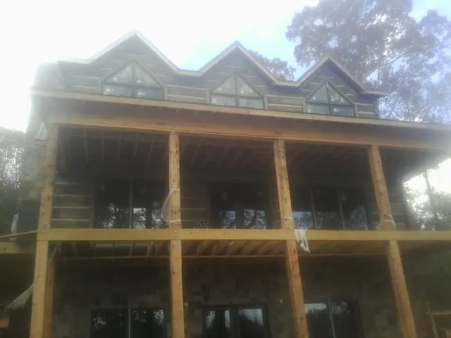 Dormers and porch framing on a large log home under construction — Roof Coating work by our crew in Jamaica